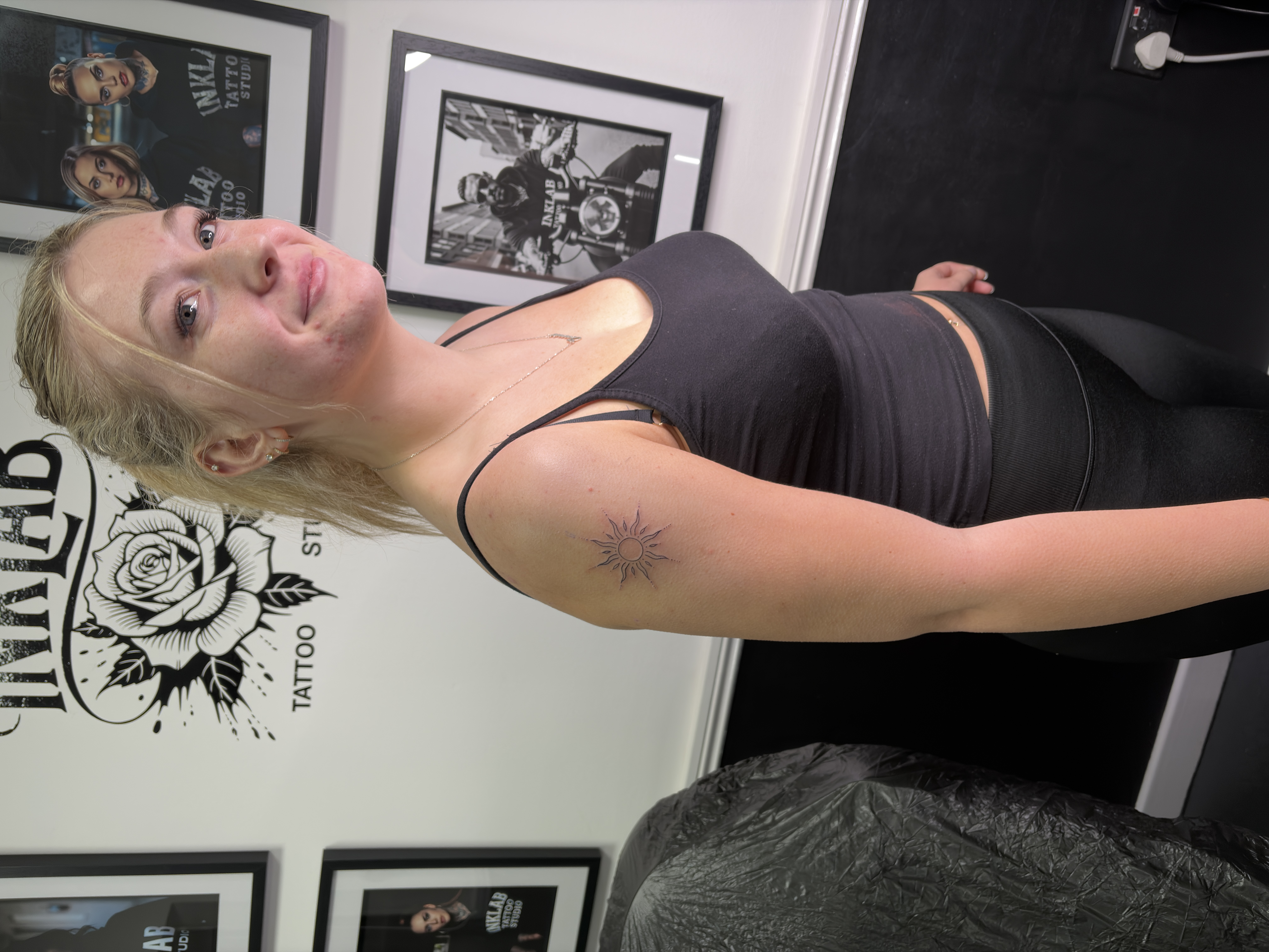 Fineline shoulder tattoo of a sun with illustrated rays and dots